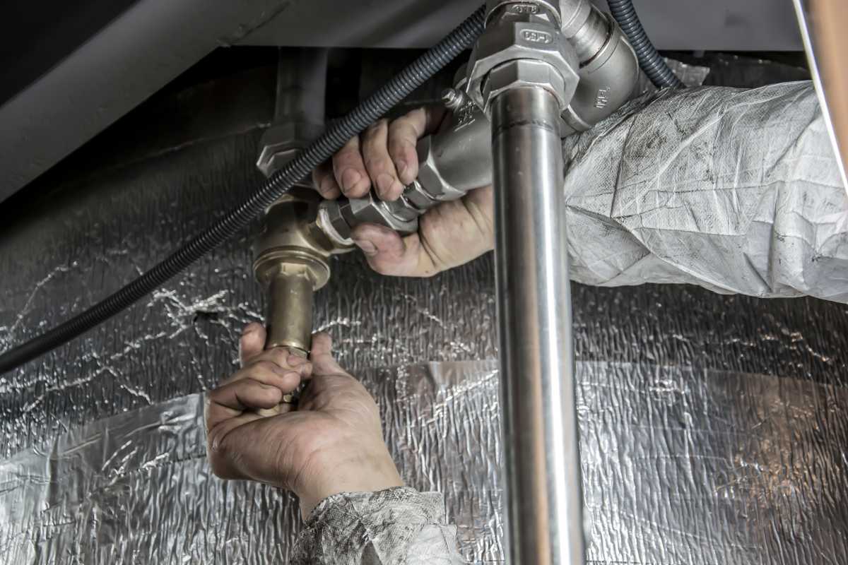 Strategie completa de management al riscurilor de apa in cladiri mixte_ de la monitorizare la electrovalve inteligente_Instalator verificand o teava de apa